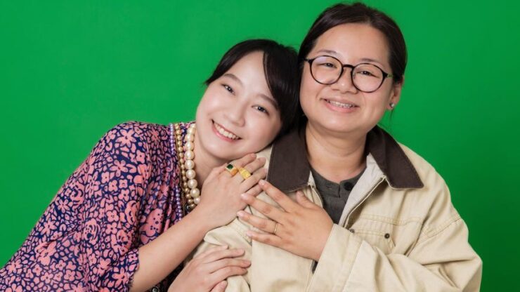 Two Asian woman side by side holding each other fondly.