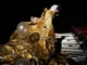 A man is stuck inside a creation of gold tin foil and balloons. this creation sits in the seats of a theatre. He looks like he's struggling to escape