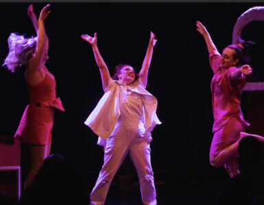 3 women jumping in the air with pink lighting
