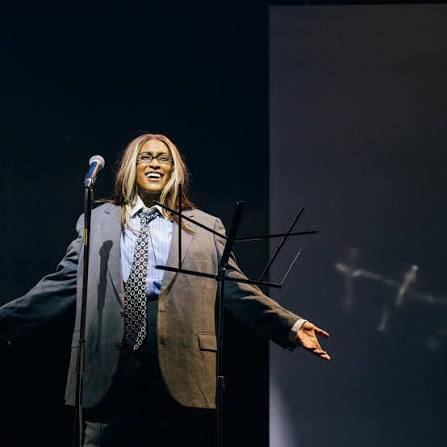 a woman holds her hand out behind a mic,